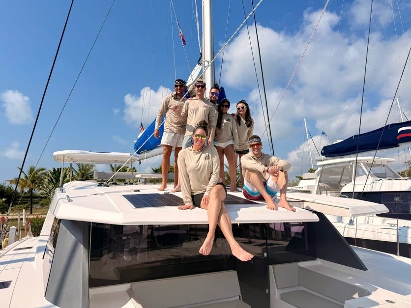 The Belize 2026 crew on the bow of the catamaran